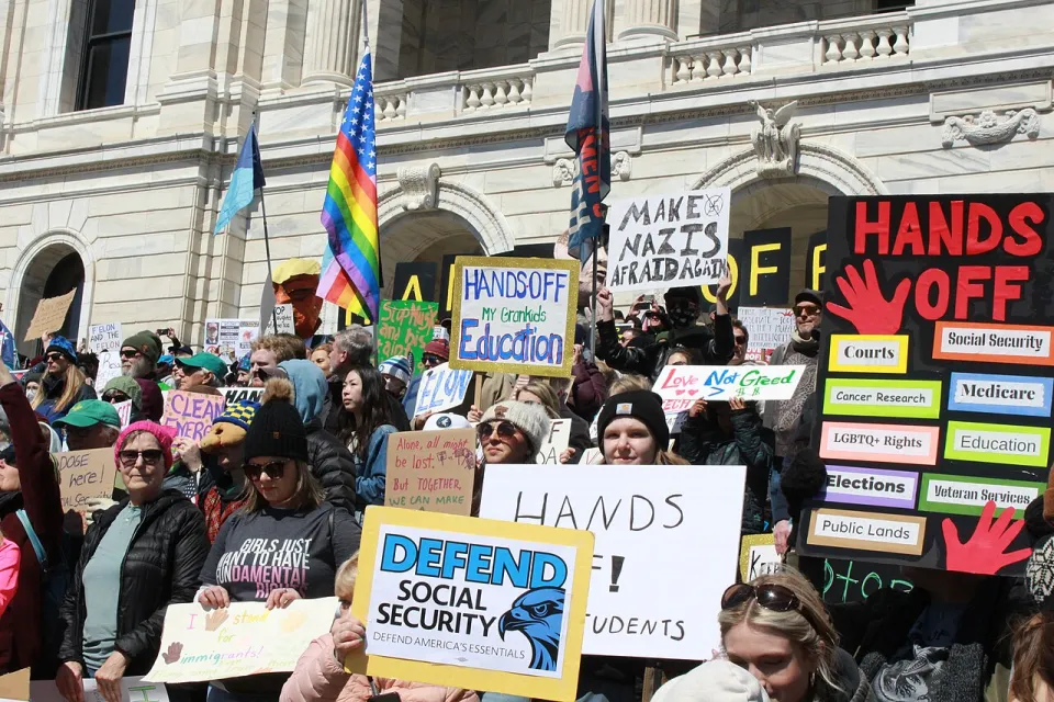 Crowd gathered with protest signs on April 5, 2025 on steps of Minnesota state capitol protesting Trump cuts to social security and other federal programs.